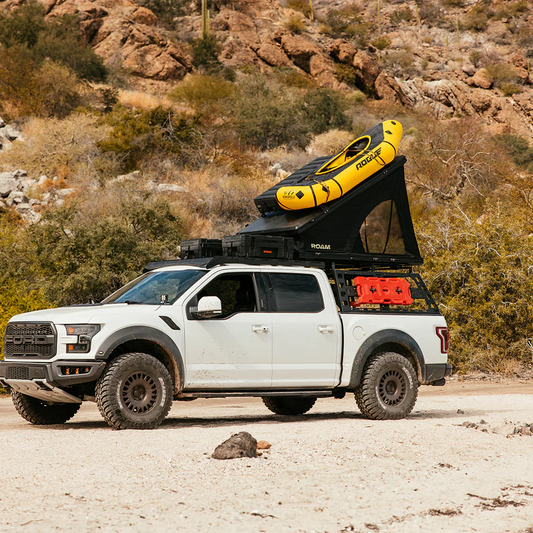 Truck with top mounted overland gear including rooftop tent, storage cases, and additional tent mounted storage